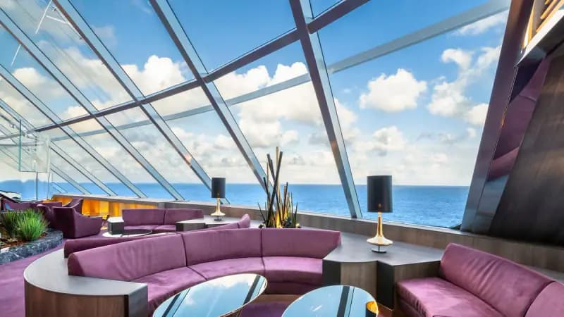 MSC Bellissima: Panorama-Lounge mit violetten Sofas und Glasfront zum Meer