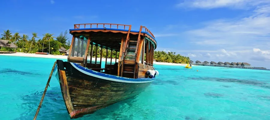 Boot auf türkiser Lagune mit Überwasserbungalows auf den Malediven